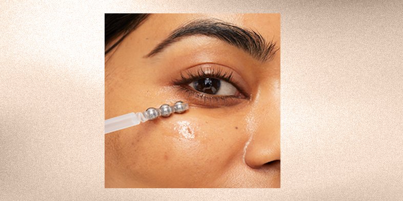 Close-up of a woman gently applying eye cream under her eyes to reduce puffiness and dark circles.